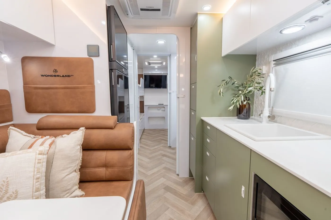 Wonderland RV interior with tan leather seating, green cabinets and a herringbone floor