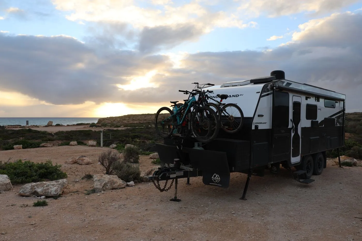 Wonderland RV caravan with bikes on the back, set up on a coastal clifftop