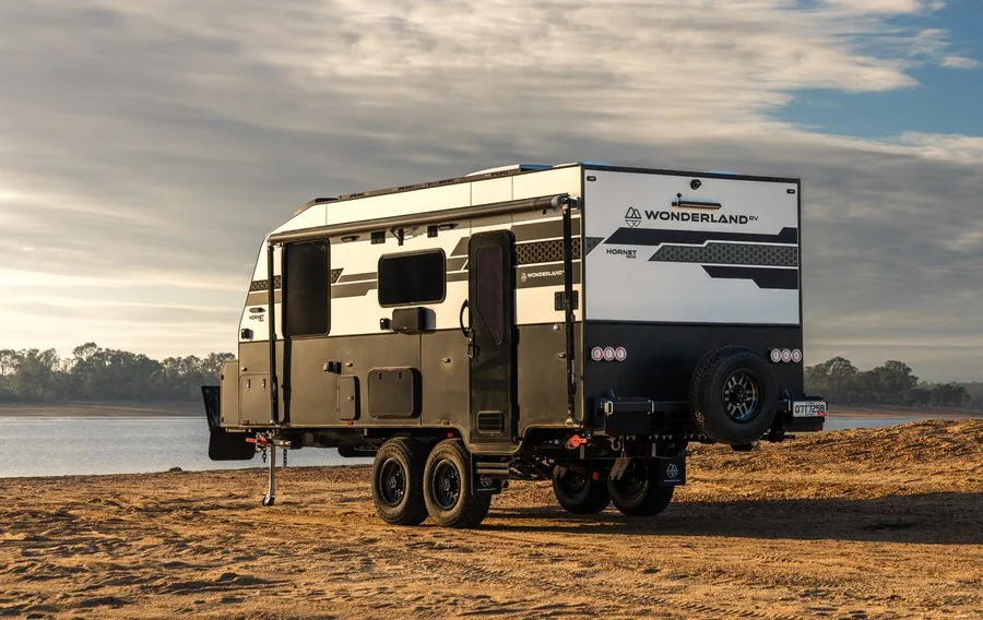 A Wonderland RV Hornet parked on the shore of a lake