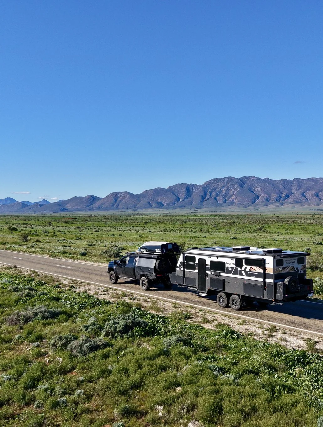 Sandy Van Travels towing their Wonderland RV past a mountain range
