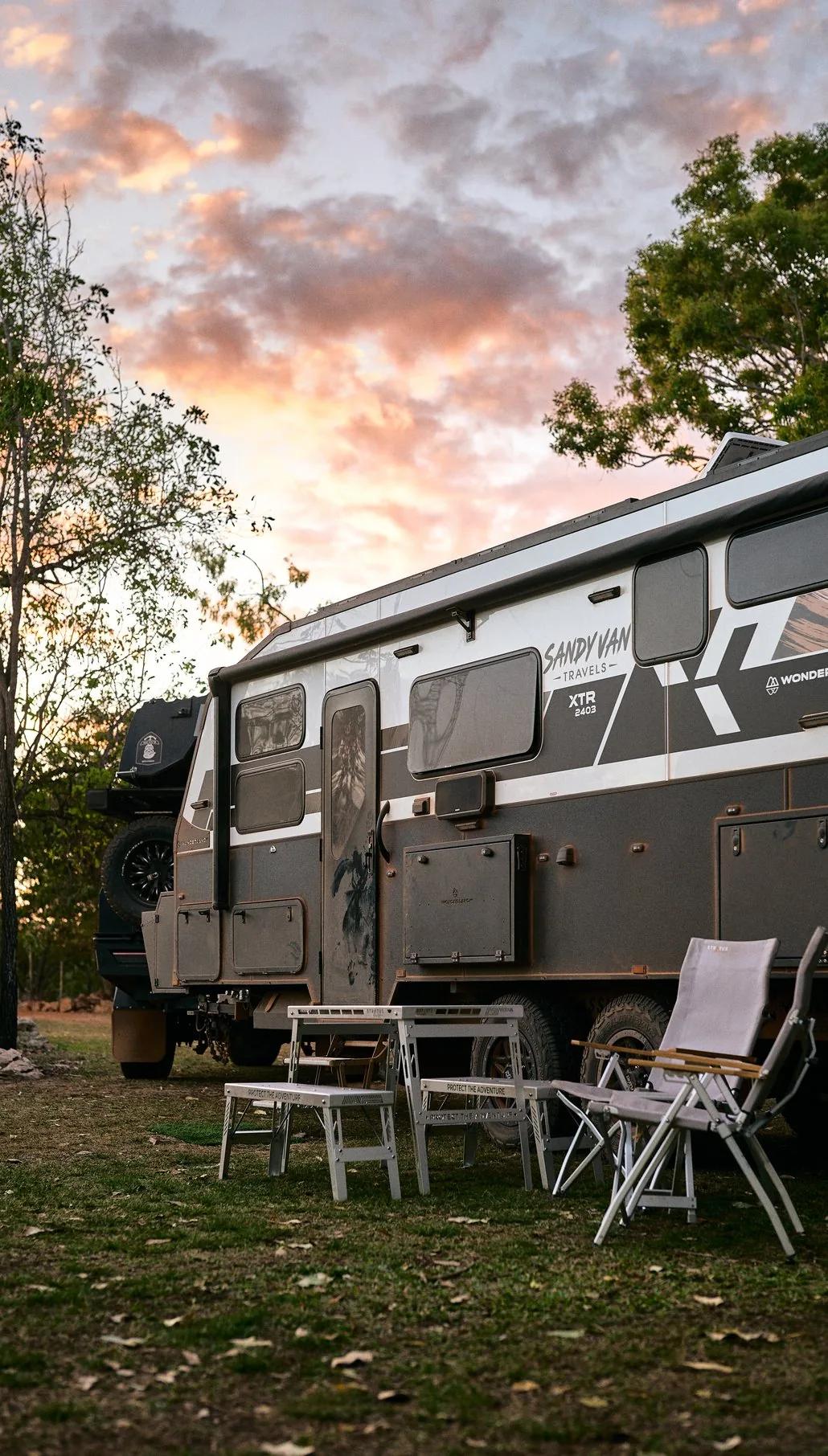 The Sandy Van Travels caravan at camp under a sunset sky