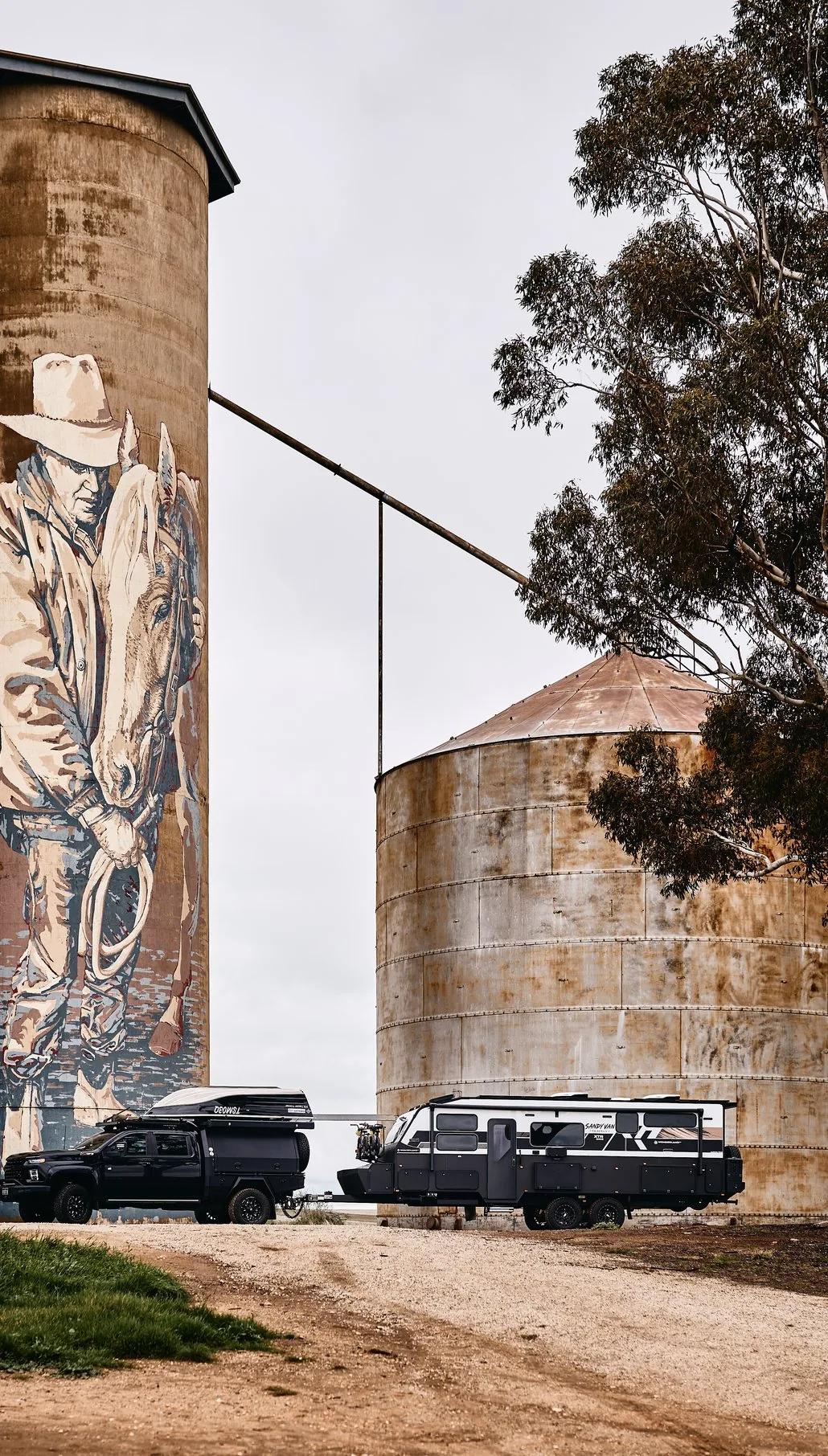 The Sandy Van Travels caravan parked beside painted silos