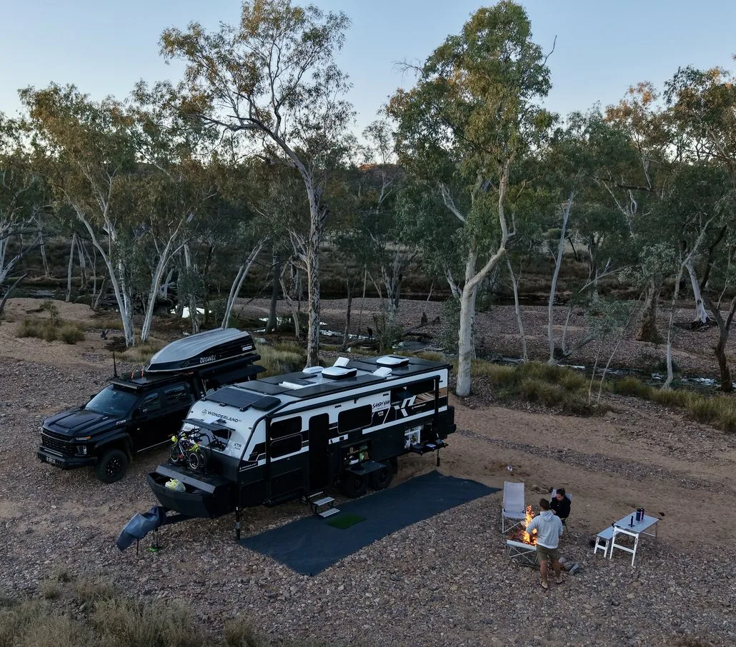 The Sandy Van Travels caravan set up at a bush camp among gum trees